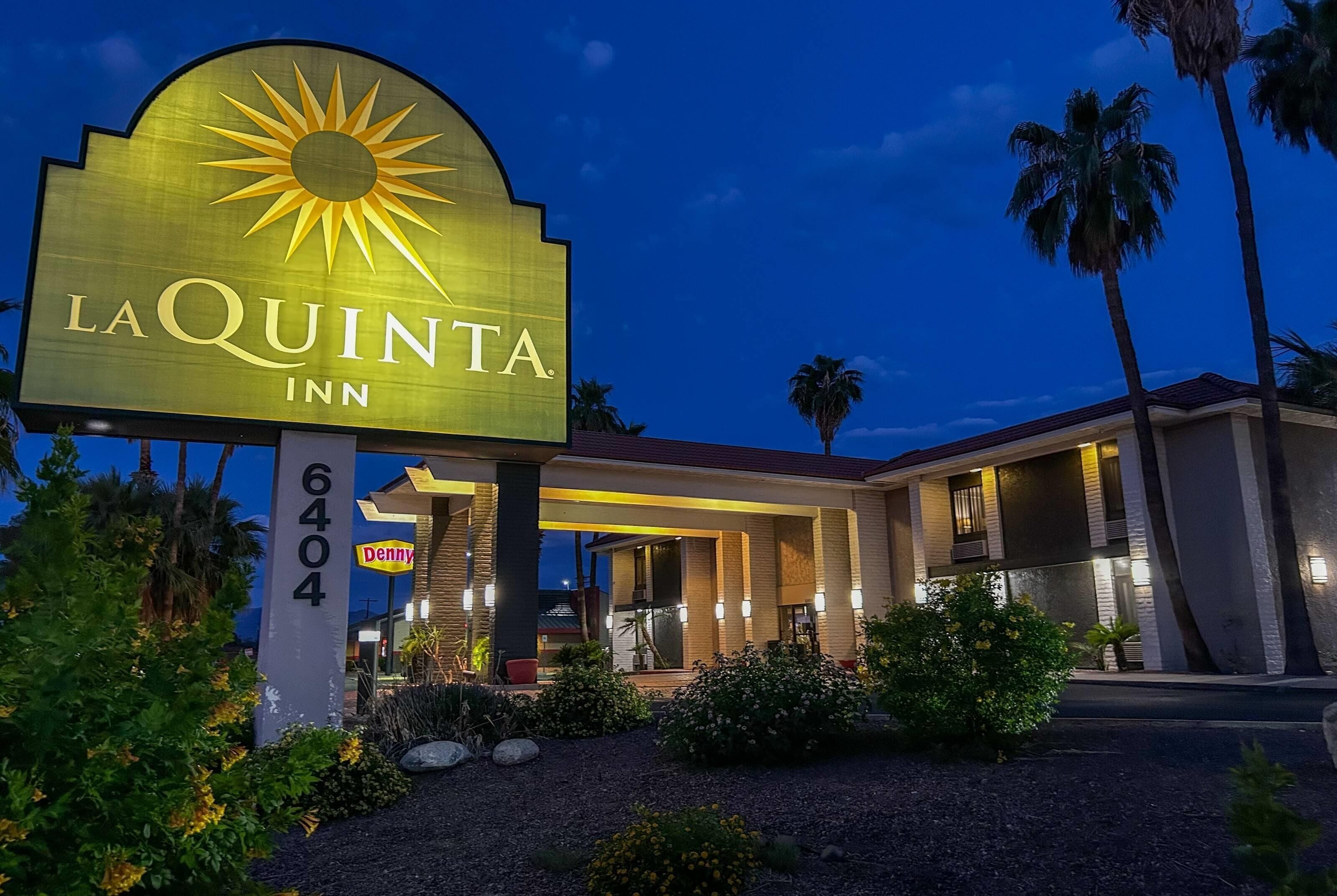 The exterior of La Quinta Inn with a prominent sign, a covered entrance, and palm trees.