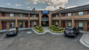 A hotel with a central entrance, parking spaces, and a sign indicating the office. - Wake Inn (Raleigh)