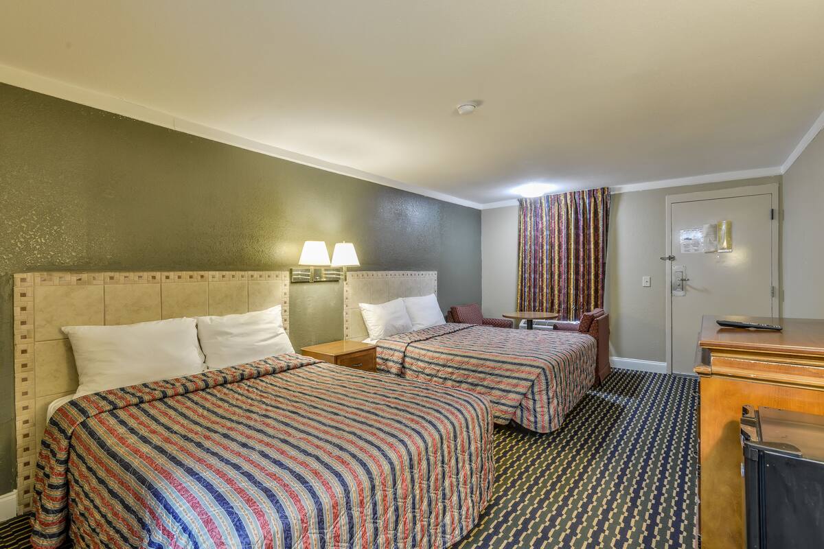 Une chambre d’hôtel avec deux lits, un bureau et une commode.