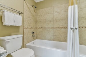 A bathroom with a bathtub, toilet, and shower.