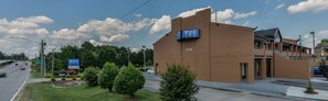 A modern building with a "Wake Inn" sign, located next to a road with a clear sky and clouds.