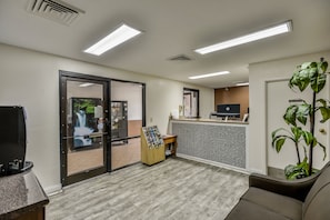 A reception area with a counter, a computer, a small plant, and a door leading outside.