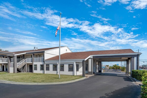 A two-story motel with a covered parking area and a flagpole.