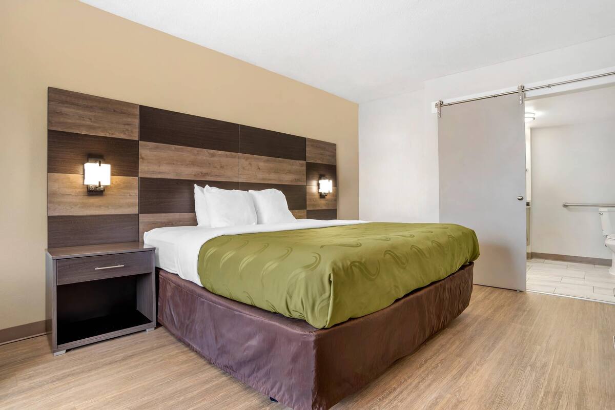 Una camera d'albergo moderna con un letto grande, un comodino e un armadio.