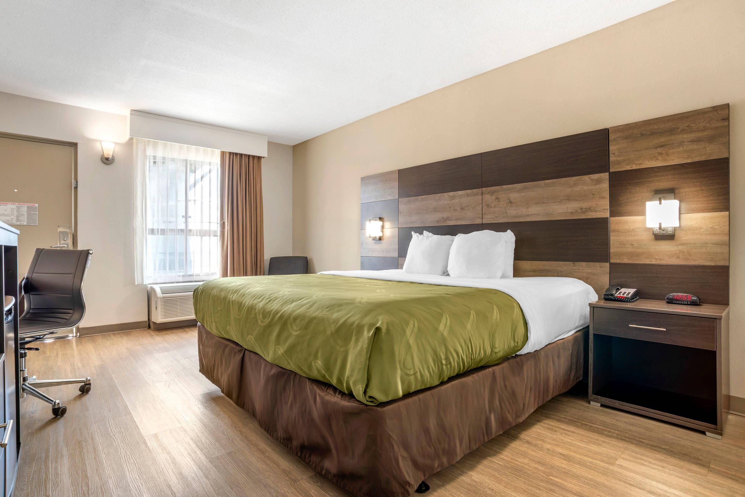 Una habitación de hotel con una cama grande, un escritorio y una silla.