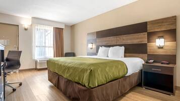 Una habitación de hotel con una cama grande, un escritorio y una silla.