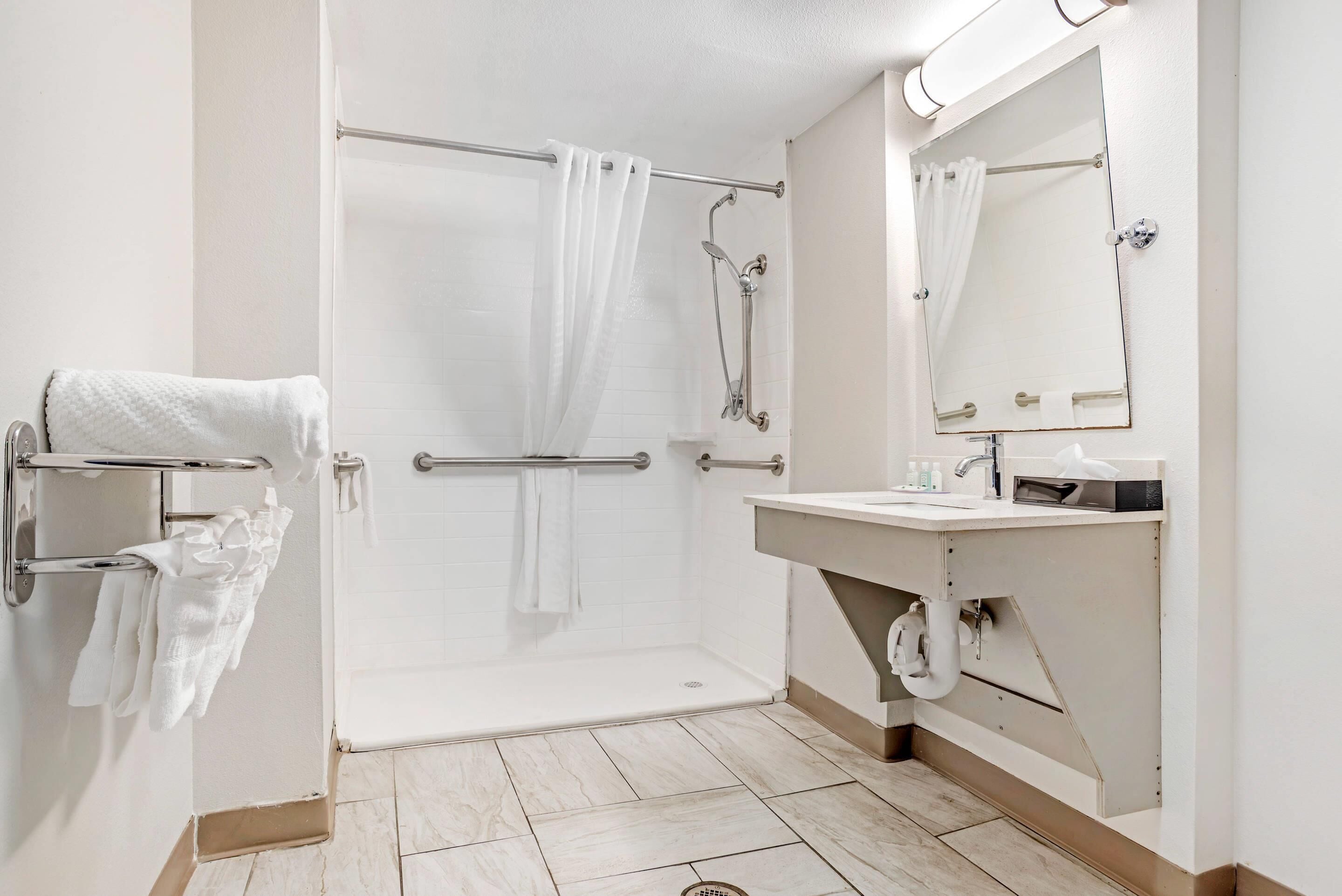 Une salle de bain moderne avec une douche à l’italienne, un meuble-lavabo avec un miroir et un porte-serviettes.