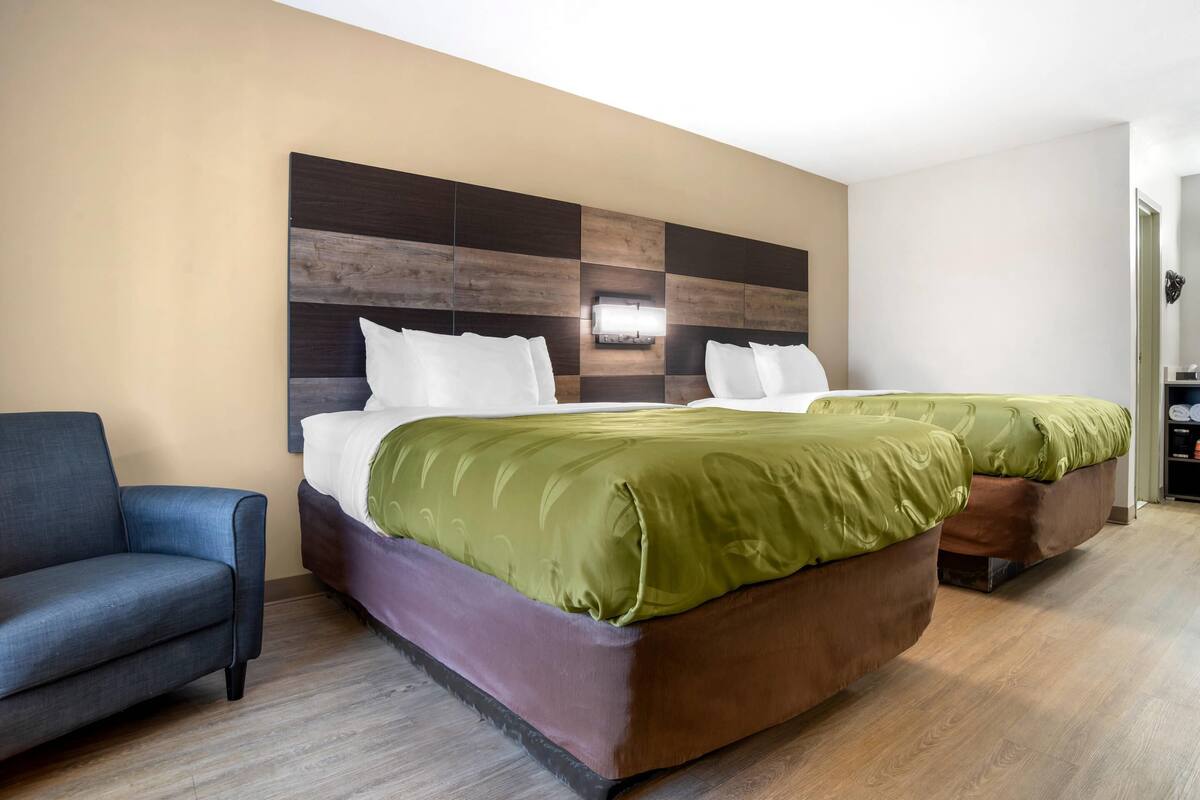 Una camera d'albergo con un letto grande, un divano e un comodino.