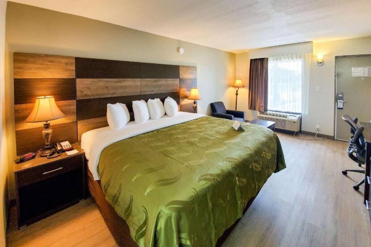 Una camera d'albergo con un letto grande, lampade sui comodini, una scrivania e una sedia.