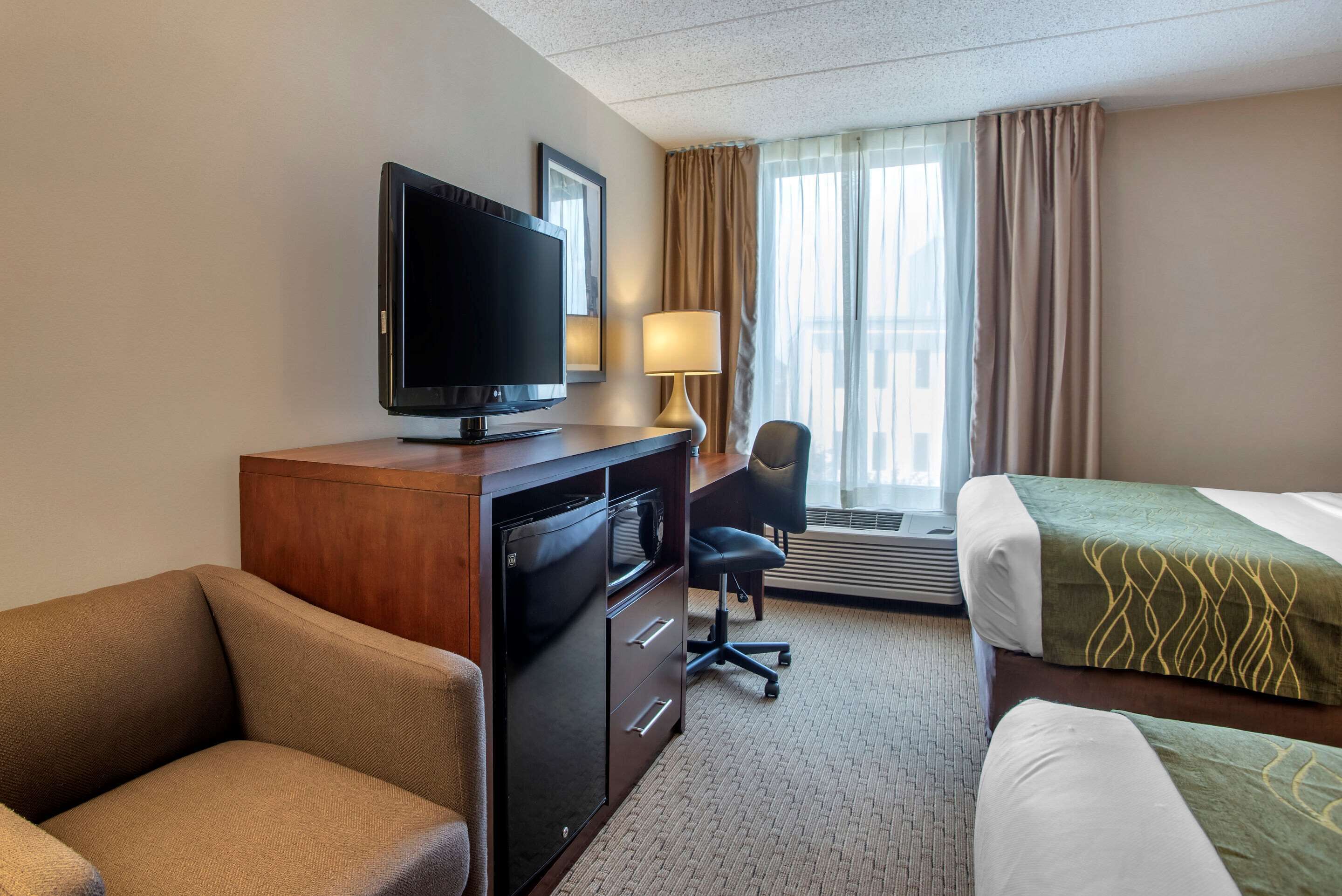 Une chambre d’hôtel comprenant un lit, un bureau avec une télévision, une chaise et une lampe.