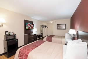 Habitación de hotel con dos camas, un escritorio, un televisor y un microondas.
