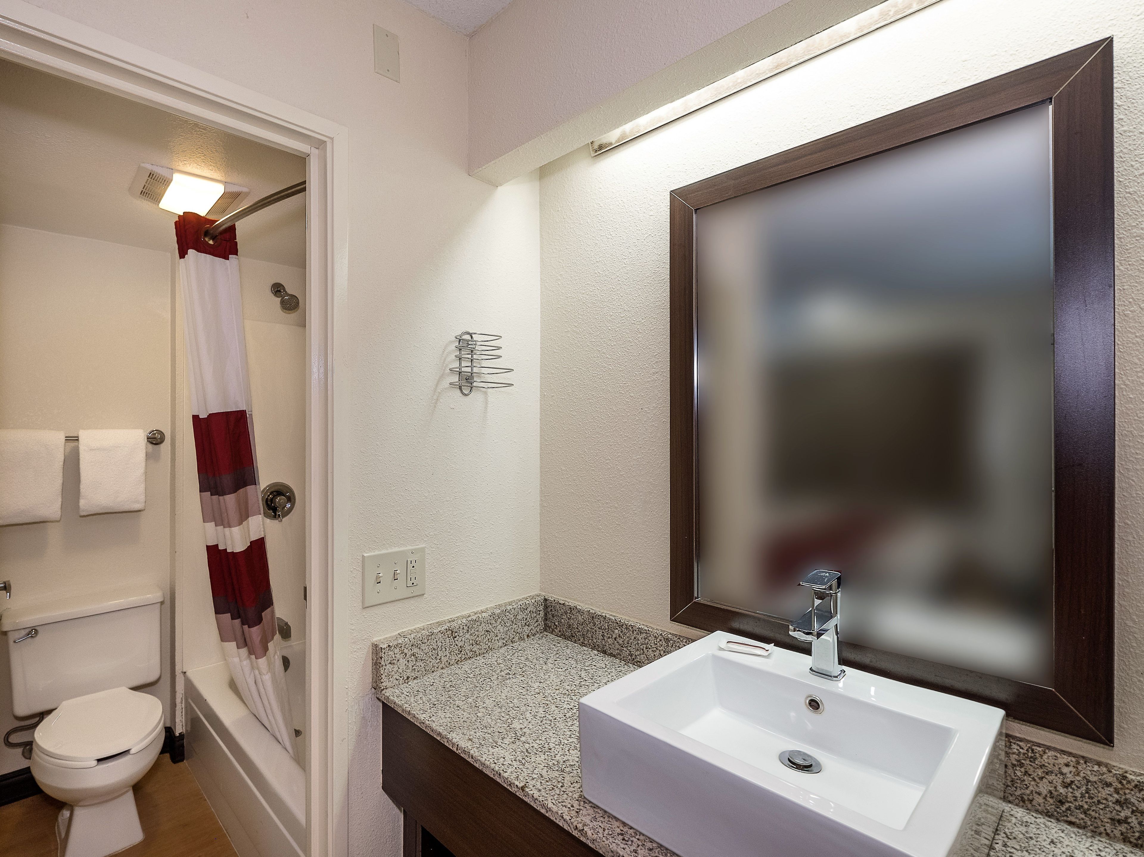 A bathroom with a white sink, a mirror, a shower curtain, and a toilet.