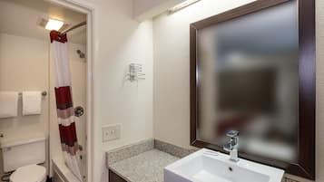 A bathroom with a white sink, a mirror, a shower curtain, and a toilet.