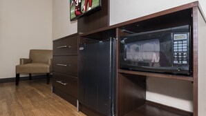 A compact kitchenette with a microwave, a refrigerator, and a television mounted above the counter. - Red Roof Inn Toledo - Maumee (Maumee)