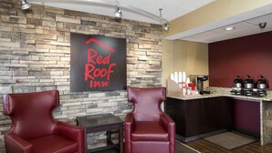 A Red Roof Inn lobby with stone walls, leather chairs, a coffee station, and a ceiling fan. - Red Roof Inn Toledo - Maumee (Maumee)
