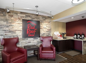 A Red Roof Inn lobby with stone walls, leather chairs, a coffee station, and a ceiling fan. - Red Roof Inn Toledo - Maumee (Maumee)