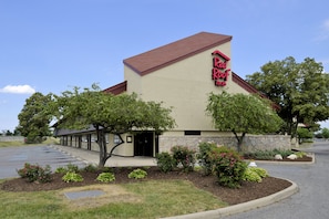A Red Roof Inn with a stone facade, a red roof, and a parking lot. - Red Roof Inn Toledo - Maumee (Maumee)