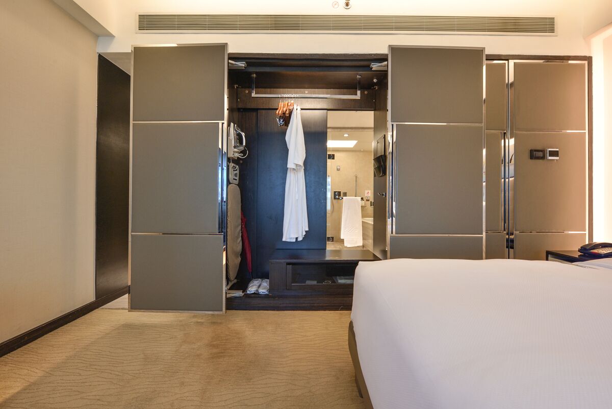 Ein Hotelzimmer mit Bett, Kleiderschrank, Spiegel und Duschbereich.