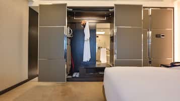 Ein Hotelzimmer mit Bett, Kleiderschrank, Spiegel und Duschbereich.