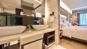 A modern hotel room with a large mirror, two sinks, a bed with white bedding, and a view of the city through large windows. - Furama Hotel Dalian (Dalian)