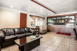 A lobby with a leather sofa, a glass-top coffee table, a reception desk, and a window with curtains. - Econo Lodge Pico Rivera (Pico Rivera)