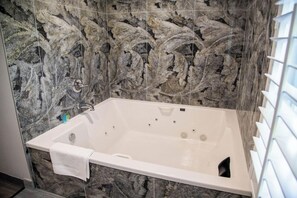 A bathroom with a marble wall, a white bathtub, and a towel rack. - Econo Lodge Pico Rivera (Pico Rivera)