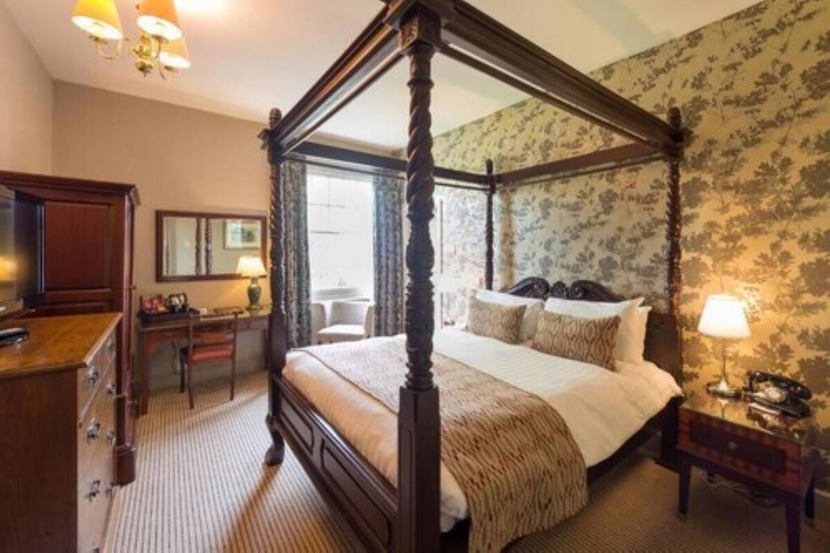 Un lit à baldaquin avec un cadre en bois, un bureau avec une chaise, un miroir et une lampe sur une table de chevet.