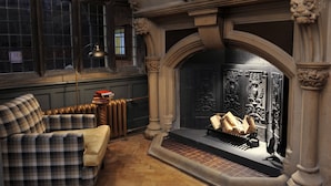 Una habitación con chimenea, sofá a cuadros y radiador.