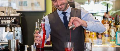 A bartender pouring a red liquid into a glass.