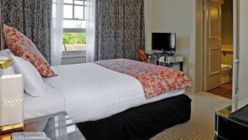 A hotel room with a bed, a television, a desk with a computer, and a bathroom visible through an open door.