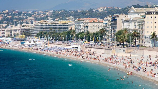 Una playa concurrida y un hotel al fondo.