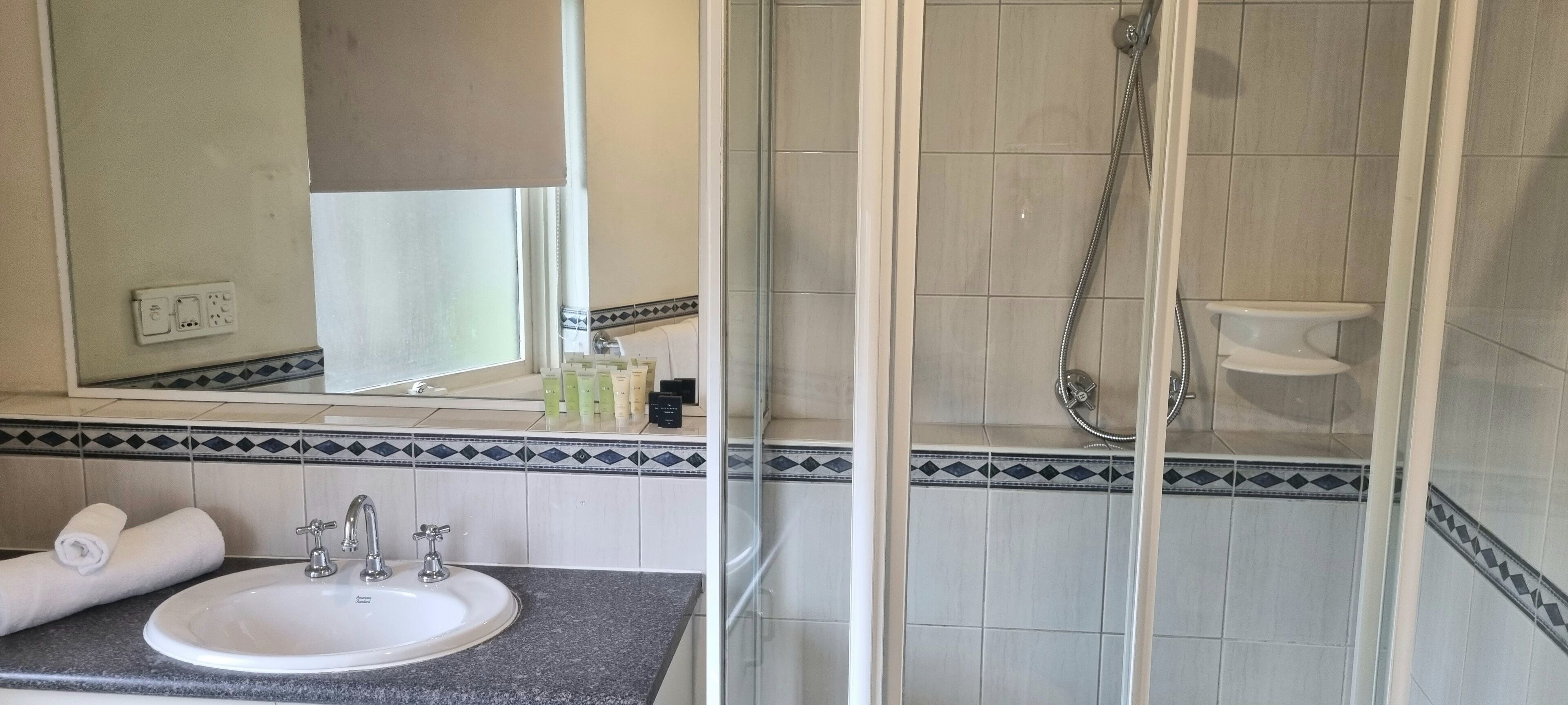 Ein Badezimmer mit Waschbecken, Spiegel und Dusche.