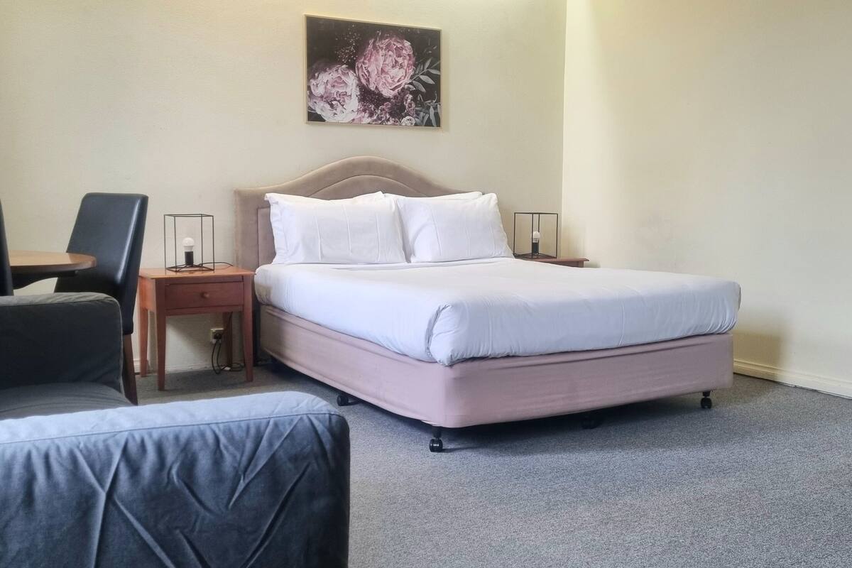 Une chambre d’hôtel avec un lit, un bureau, une chaise et une petite table.