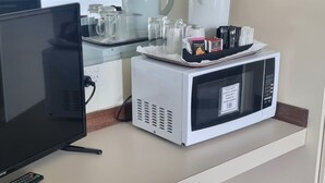 Ein Hotelzimmer mit Fernseher, Mikrowelle, Kaffeemaschine und einem Tablett mit verschiedenen Gegenständen.