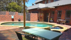 Ein Garten mit Swimmingpool, Terrassentisch und Stühlen.