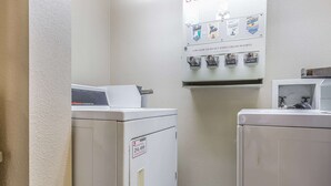 A laundry area with two washers and dryers, a coin-operated machine, and a sign indicating the coin slot locks out when empty. - Quality Inn Mount Vernon, IL (Mount Vernon)