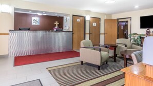 A reception area with a desk, chairs, a red carpet, and a television mounted on the wall. - Quality Inn Mount Vernon, IL (Mount Vernon)