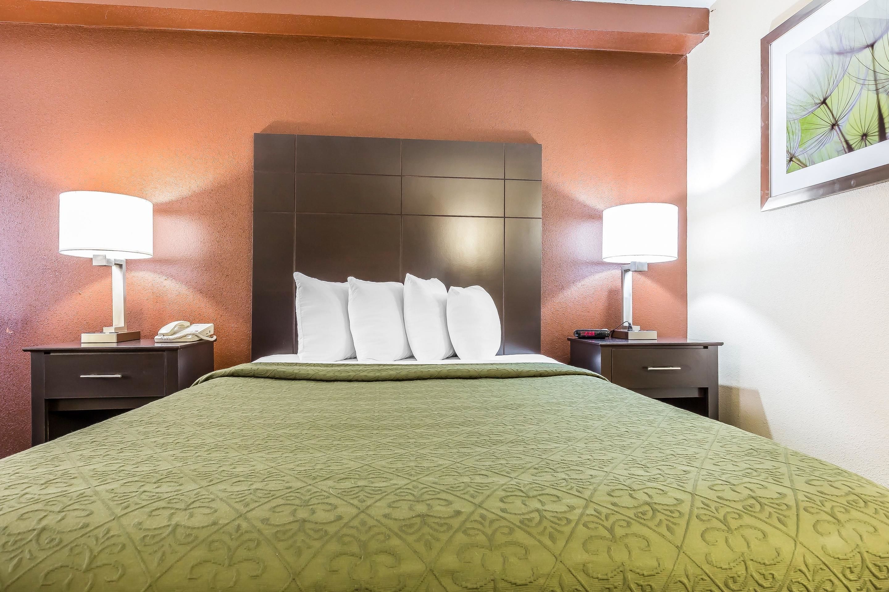 Ein Hotelzimmer mit einem großen Bett, zwei Nachttischen, einer Kopfteil und einem gerahmten Bild an der Wand.