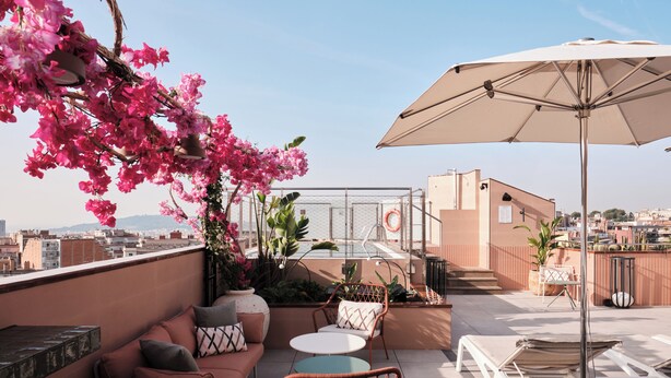 Une terrasse sur le toit, aménagée avec des sièges, une table et un grand parasol.