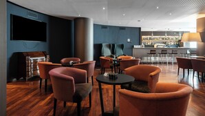 Un espace de détente moderne offrant de nombreuses options d’assises, un bar et un écran de télévision.