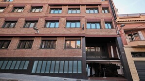 A multi-story building with a brick facade, numbered 74 and 68, featuring large windows and a storefront named Catalonia Park Putxet.