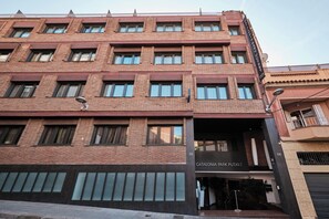 Un edificio de varios pisos con fachada de ladrillo, con los números 74 y 68, grandes ventanales y una tienda llamada Catalonia Park Putxet.