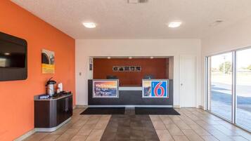 A reception area with a counter, a digital display, and a view of the parking lot.