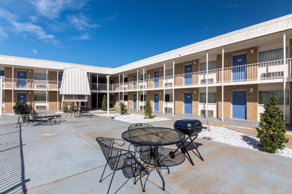 A multi-story motel with outdoor seating and a barbecue area.