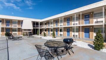 A multi-story motel with outdoor seating and a barbecue area.