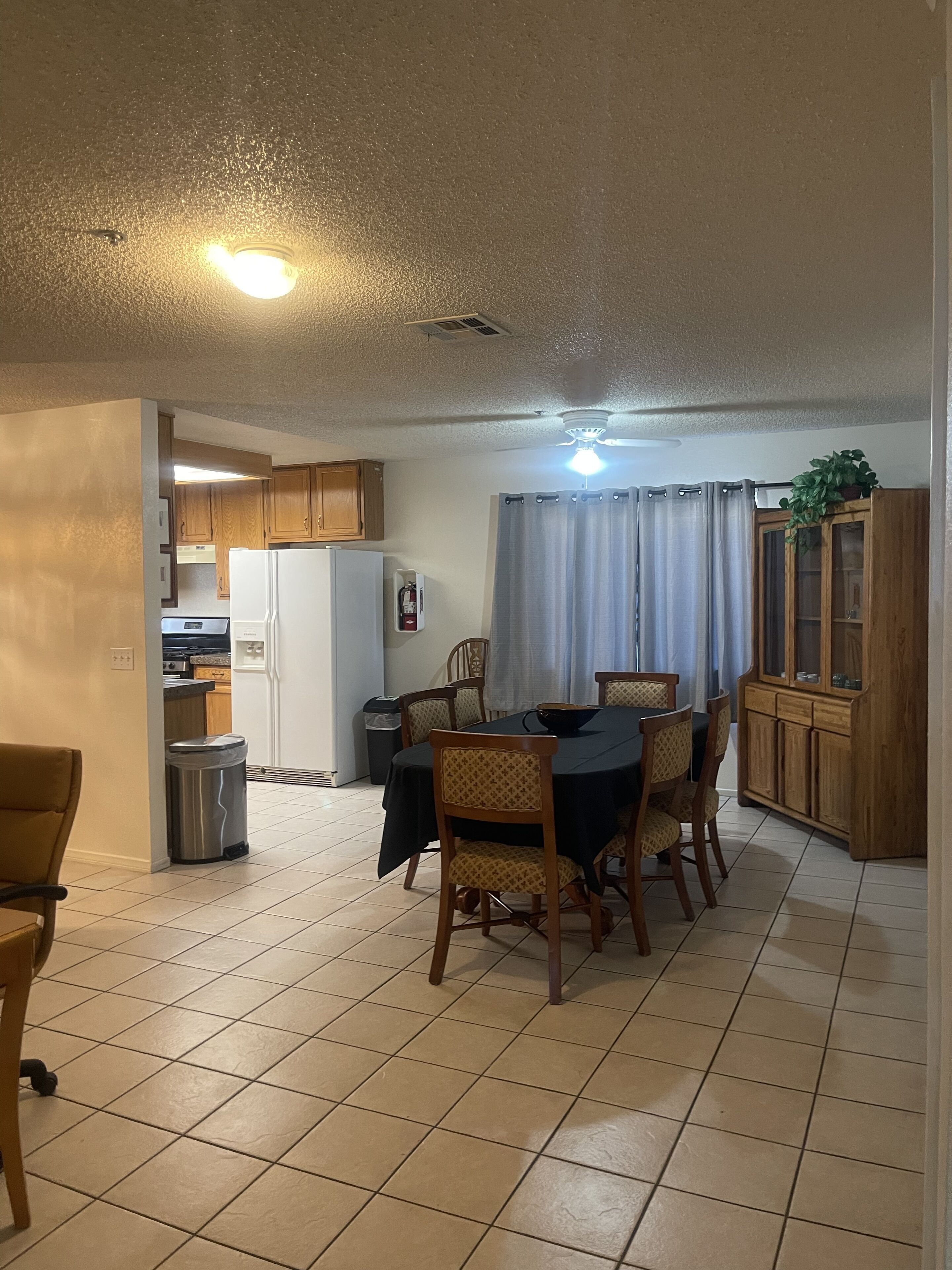 A compact kitchen with wooden cabinets, a refrigerator, and a dining area with a table and chairs.