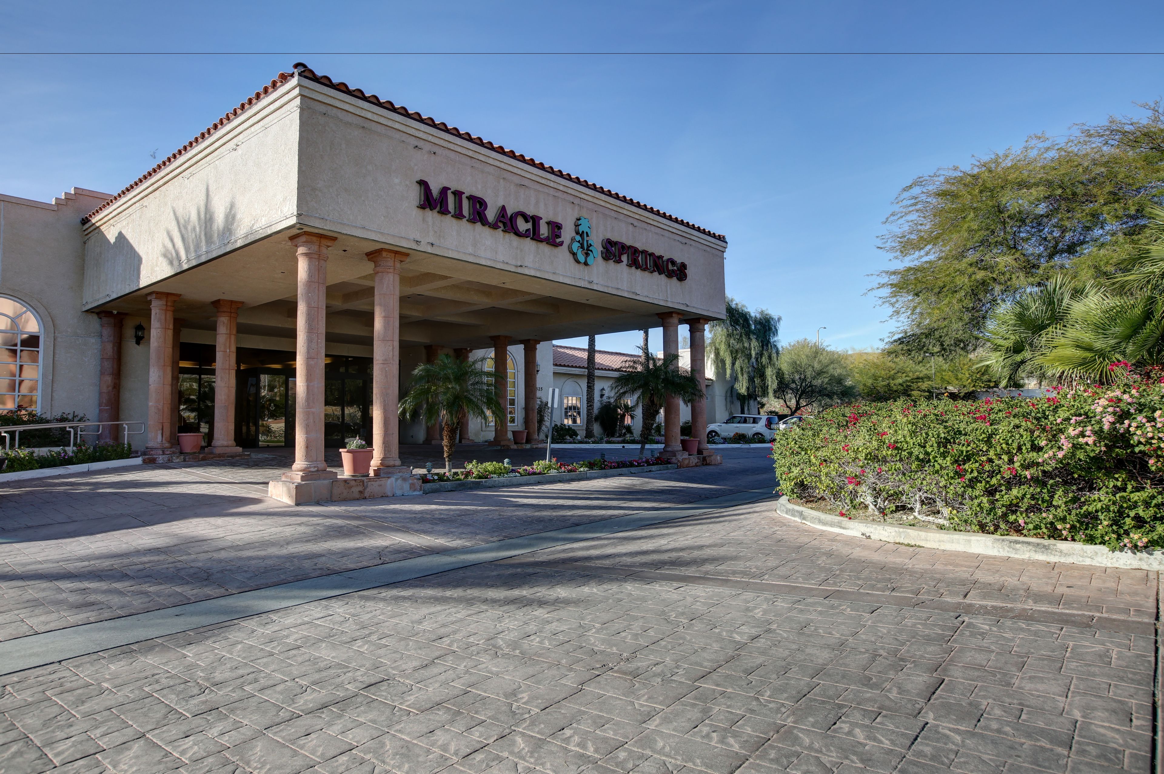 Un edificio con una entrada cubierta, columnas y un letrero que dice "Miracle Springs".