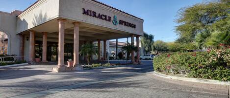 A building with a covered entrance, columns, and a sign that reads "Miracle Springs."