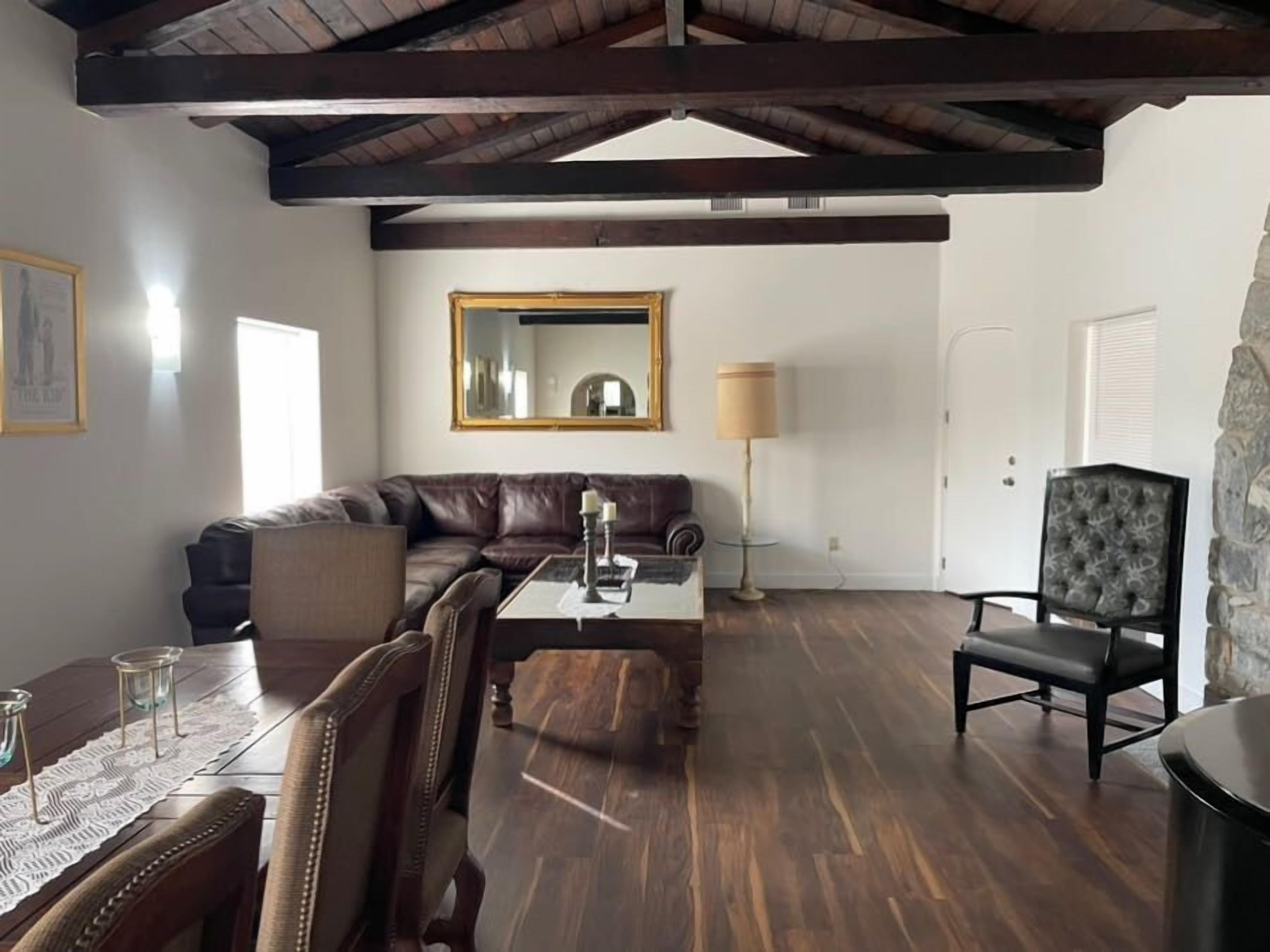 A spacious living room with a dark brown leather sofa, a wooden coffee table, and a stone accent wall.