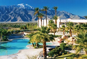 A resort with a swimming pool, palm trees, and a mountain in the background. - Miracle Springs Resort & Spa (Desert Hot Springs)